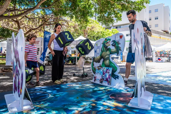 Una familia juega a un juego de mesa gigante con dados enormes al aire libre