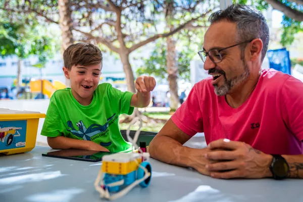 Un niño y un monitor ríen en un taller de robótica con LEGO