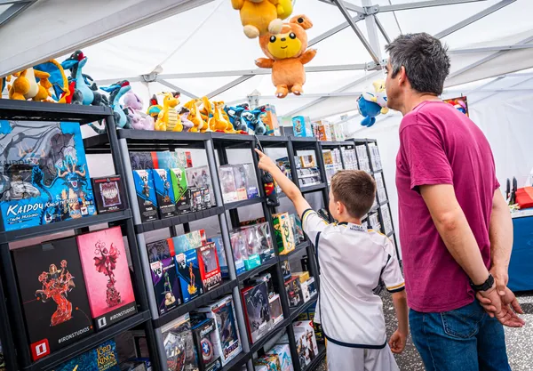 Un niño señala figuras y peluches en un puesto de coleccionables